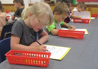 Children engaging in a creative craft activity with pencil crayons at their desks